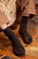 Person wearing brown ribbed socks on a wooden floor