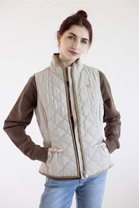 A woman modeling a quilted zip-front vest over a brown long-sleeve shirt and blue jeans, photographed against a plain light background.