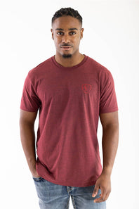 A man wearing a heathered maroon crewneck t-shirt with a small red shield logo on the left chest, paired with blue jeans, photographed against a plain white background.