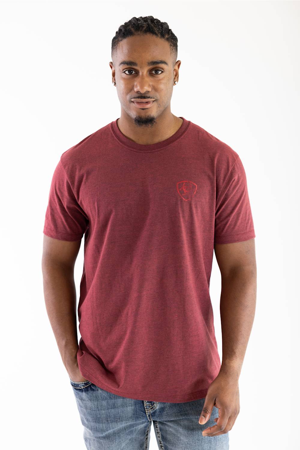 A man wearing a heathered maroon crewneck t-shirt with a small red shield logo on the left chest, paired with blue jeans, photographed against a plain white background.