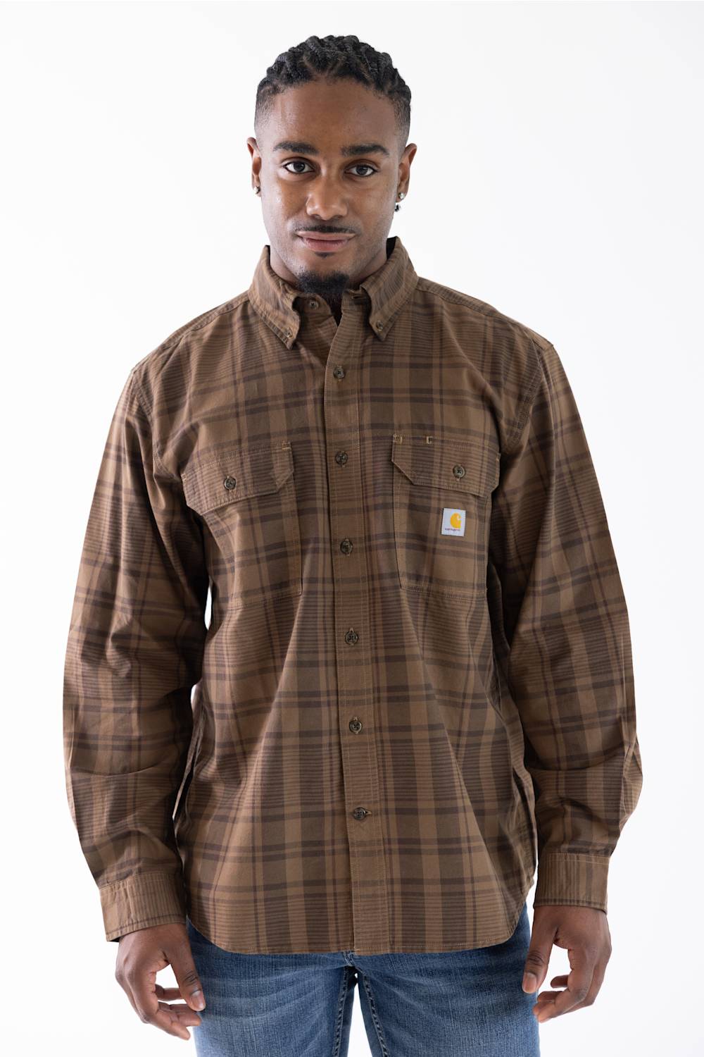 A man wearing a brown and tan plaid button-down shirt by Carhartt, featuring a small white brand patch on the left chest pocket.