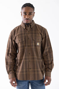 A man wearing a brown and tan plaid button-down shirt by Carhartt, featuring a small white brand patch on the left chest pocket.