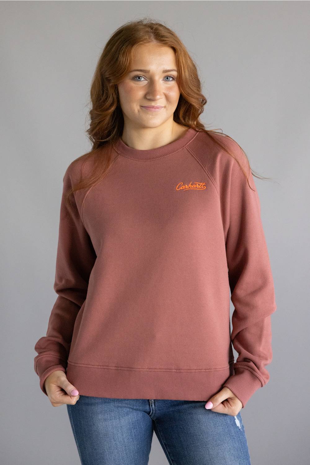 Dark red colored sweatshirt with orange Carhartt cursive letters on chest 