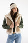 Carhartt Satin Lined Knit Headband in Oat Milk worn with a fleece vest, olive long-sleeve top, and jeans