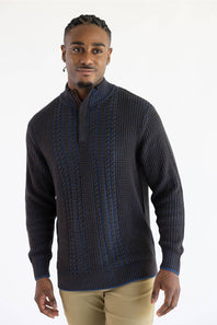 A man wearing a dark brown textured knit mock-neck sweater with vertical blue and white stripe patterns, paired with beige trousers, against a plain white background.