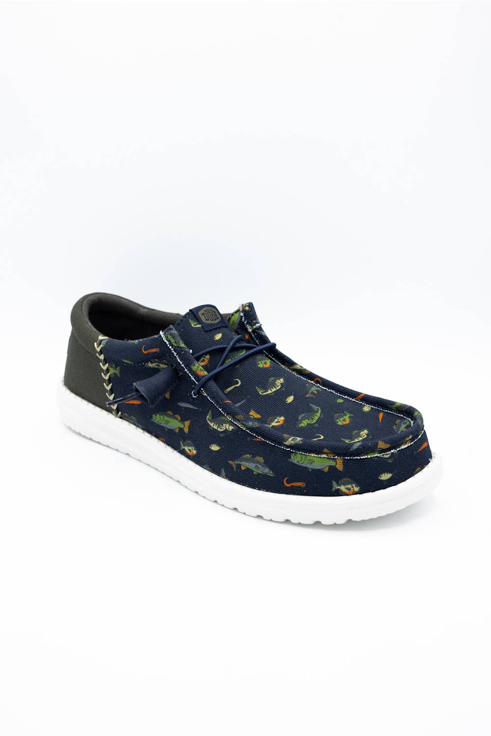 A single casual slip-on shoe with a navy blue canvas upper covered in a colorful alligator print, featuring a dark gray heel tab, matching laces, and a white sole, shown on a white background.