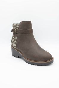 A single women's ankle boot in dark brown faux suede, featuring a textured knit pattern panel on the back collar and a matching brown strap with a silver-tone buckle, set against a plain white background.