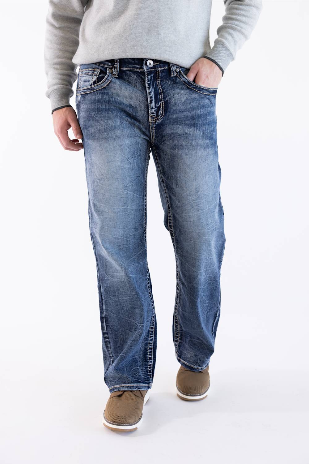 Men's medium wash straight-leg jeans styled with a grey crewneck sweater, subtle whiskering, and brown casual shoes.