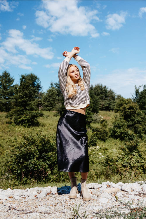 women in black skirt with trees in background