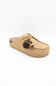 A tan suede slip-on mule shoe with a thick platform sole, decorative laces, and a hanging tassel ornament with beads, shown against a plain white background.