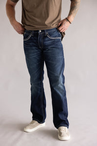 Ariat M5 Slim Stretch Coltrane Straight Leg Jeans for Men; Person wearing blue jeans and a brown shirt on a plain background