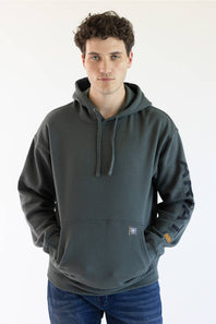 A man wearing a dark green pullover hoodie with drawstrings and a kangaroo pocket, paired with blue jeans, standing against a plain white background.