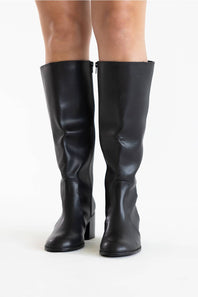 A pair of black knee-high leather boots with block heels, shown on a model's feet against a plain white background.