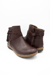 A pair of dark brown faux-leather ankle boots with side bow details and a cork-look sole, shown on a white background.