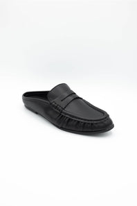 A single black leather loafer-style mule shoe with a decorative strap across the vamp, photographed on a clean white studio background.