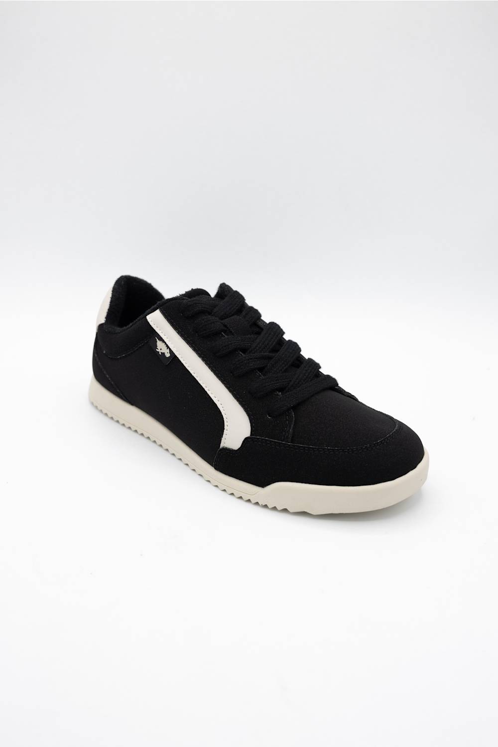 A black low-top sneaker with a white side stripe, black laces, and a white sole, photographed on a seamless white background.