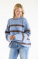 A woman wearing a light blue knit sweater with horizontal brown stripes and light-wash blue jeans, standing against a plain white studio background.