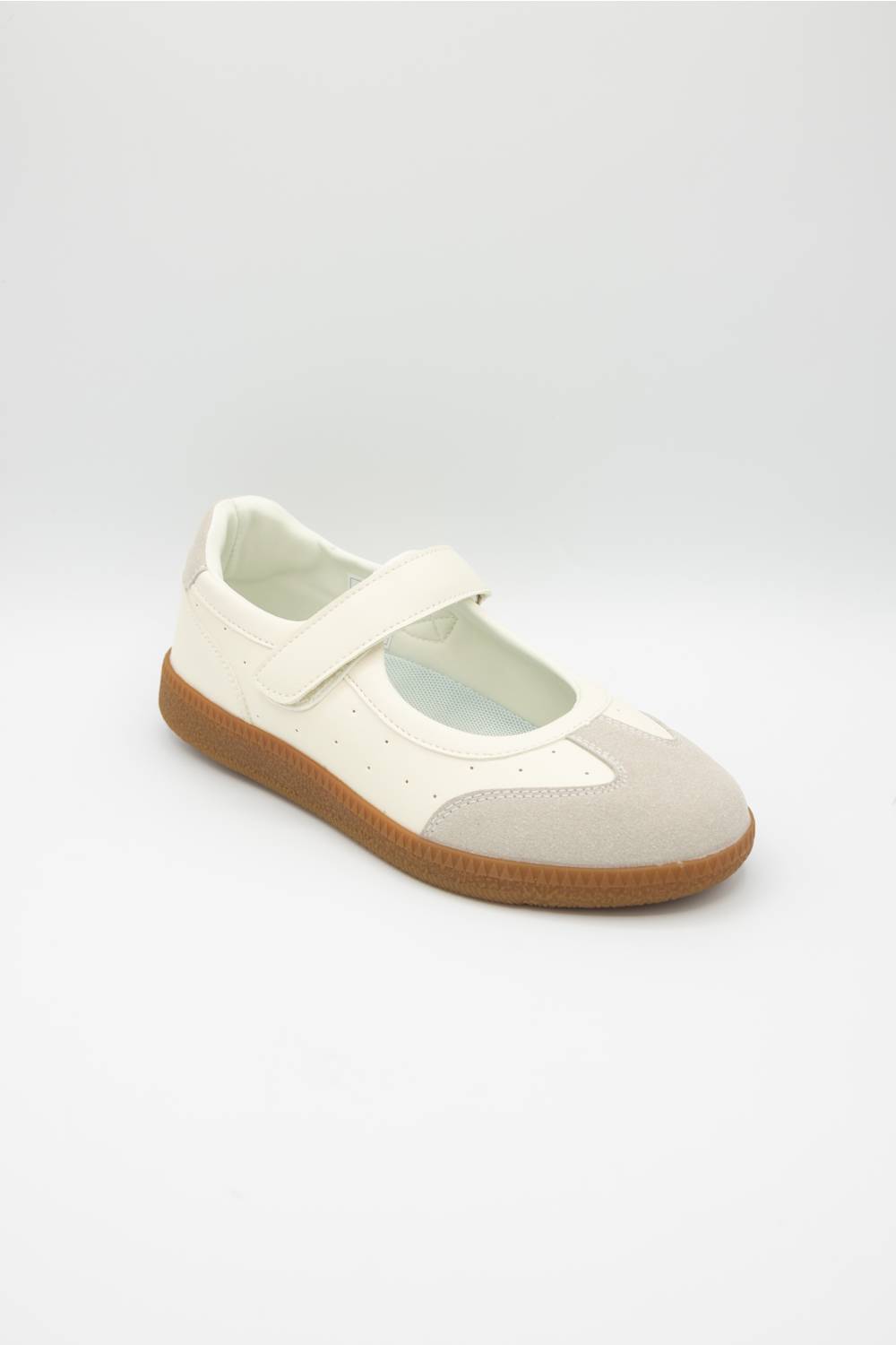 A single Mary Jane shoe in off-white and light beige suede, featuring a brown gum sole, photographed on a light gray studio background.