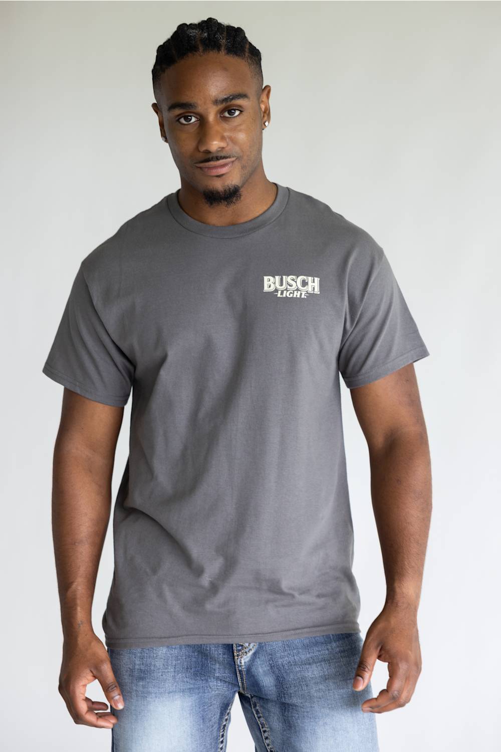 A man wearing a dark gray crewneck t-shirt with a white 'BUSCH Light' logo on the left chest, paired with blue jeans, standing against a light gray background.