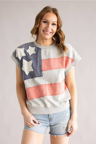 Woman wearing a colorful flag-themed shirt with stars and stripes on a plain background
