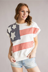 Woman wearing a colorful American flag shirt against a plain background