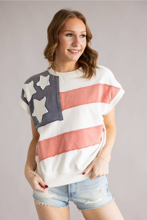 Woman wearing a colorful American flag shirt against a plain background