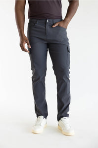 A person wearing dark charcoal gray cargo pants, a dark brown t-shirt, and white sneakers, standing against a plain white studio background.