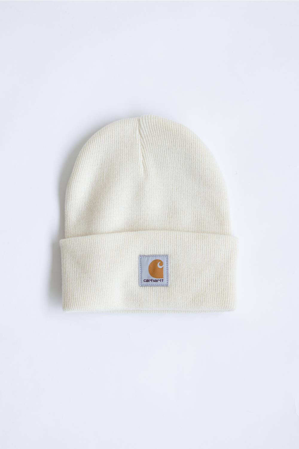 An off-white ribbed knit beanie hat featuring a small Carhartt brand patch on the front cuff, set against a plain white background.