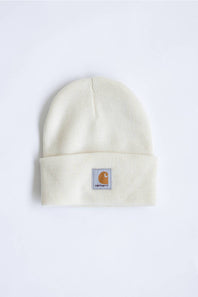 An off-white ribbed knit beanie hat featuring a small Carhartt brand patch on the front cuff, set against a plain white background.