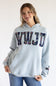 A woman wearing a light blue hoodie with a floral-patterned 'KWJD' graphic across the chest, paired with blue jeans, against a plain white background.