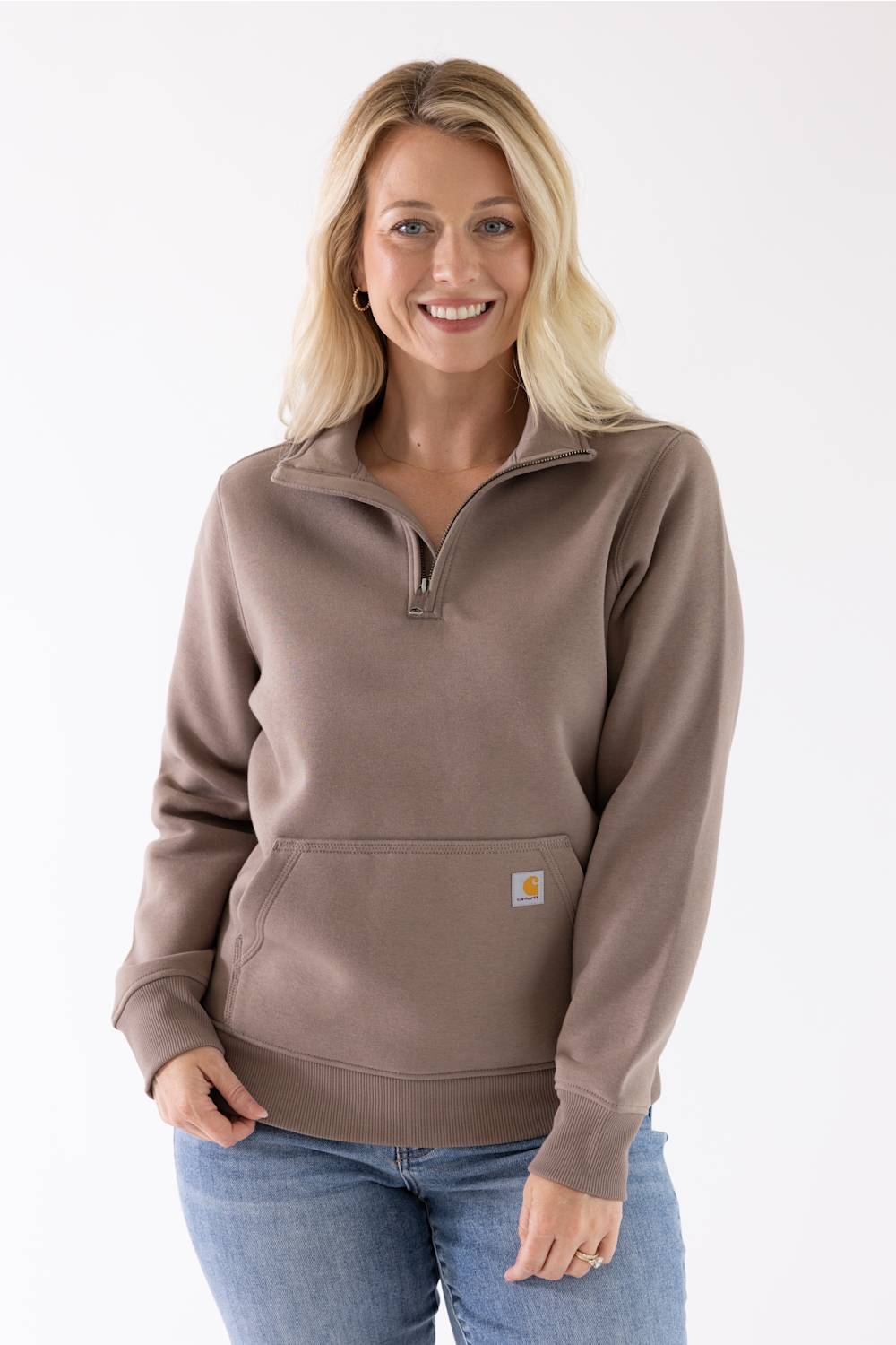 Close-up front view of a stone brown Carhartt quarter-zip sweatshirt featuring a mock-neck collar and a front kangaroo pocket with a small logo patch.