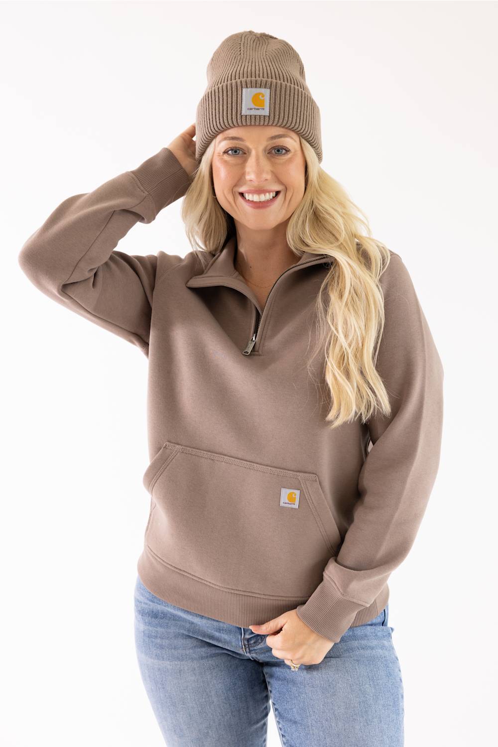 Woman wearing a Carhartt Stone Brown cuffed rib knit beanie and a matching brown half-zip sweatshirt.
