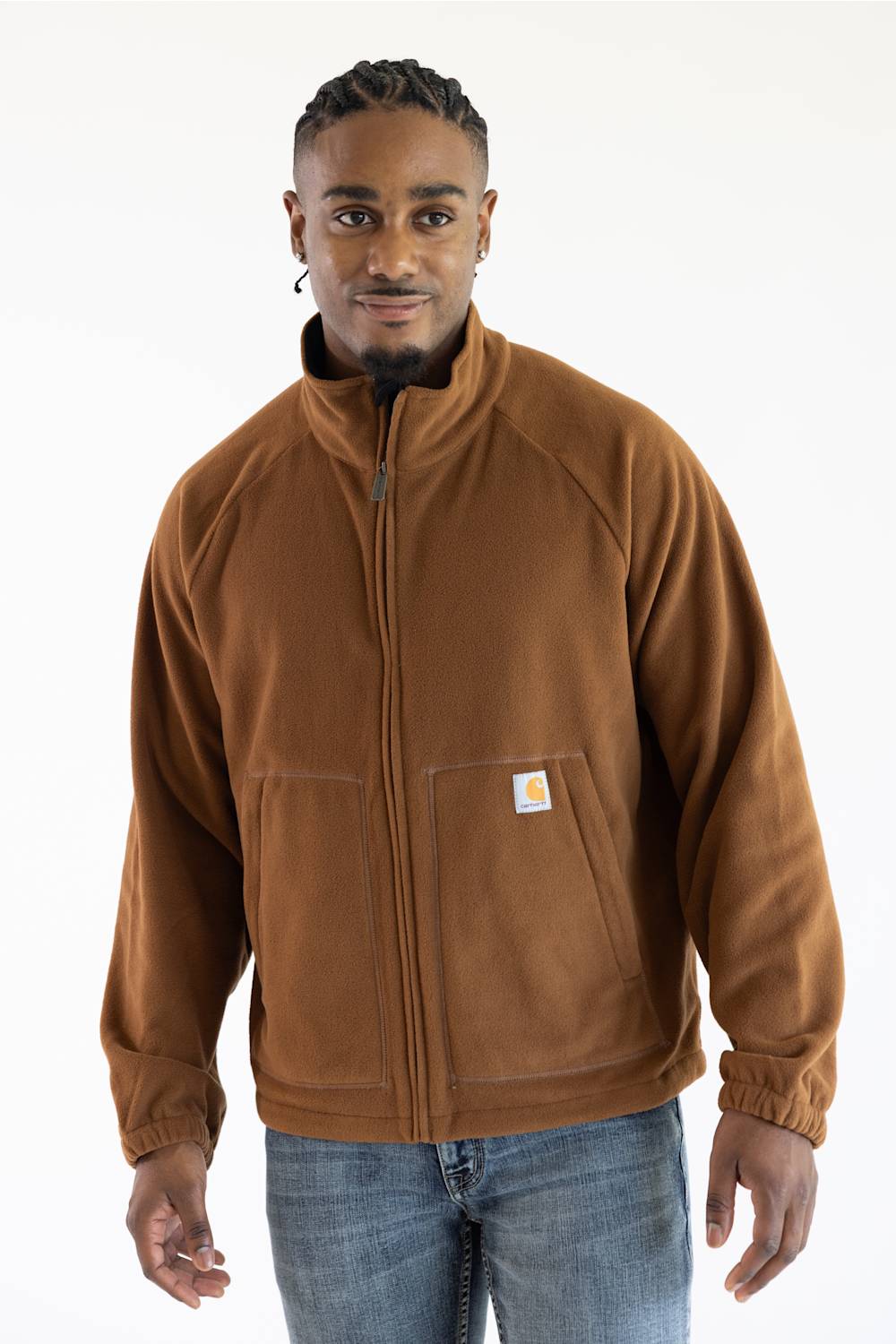 Male model standing against a white background, wearing a brown Carhartt Elkhart zip-up fleece jacket with a mock neck collar and a square Carhartt logo patch on the front pocket.