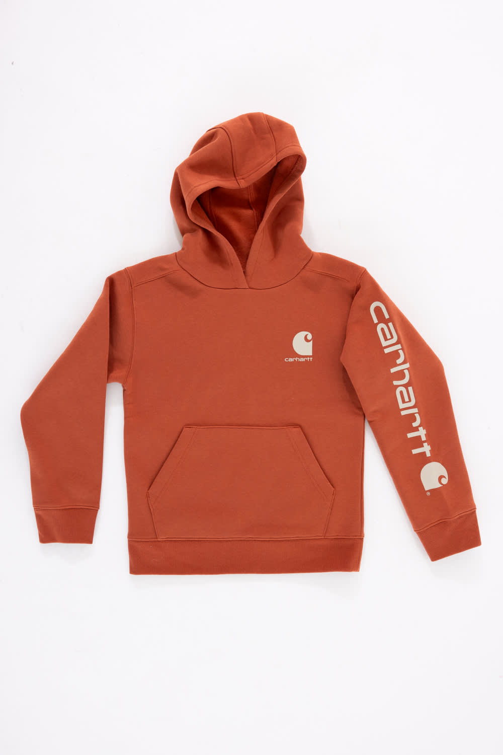 Front view of a boys' burnt brick orange pullover hoodie featuring a front kangaroo pocket, a small white Carhartt logo printed on the left chest, and a bold white Carhartt logo along the left sleeve against a plain white background.