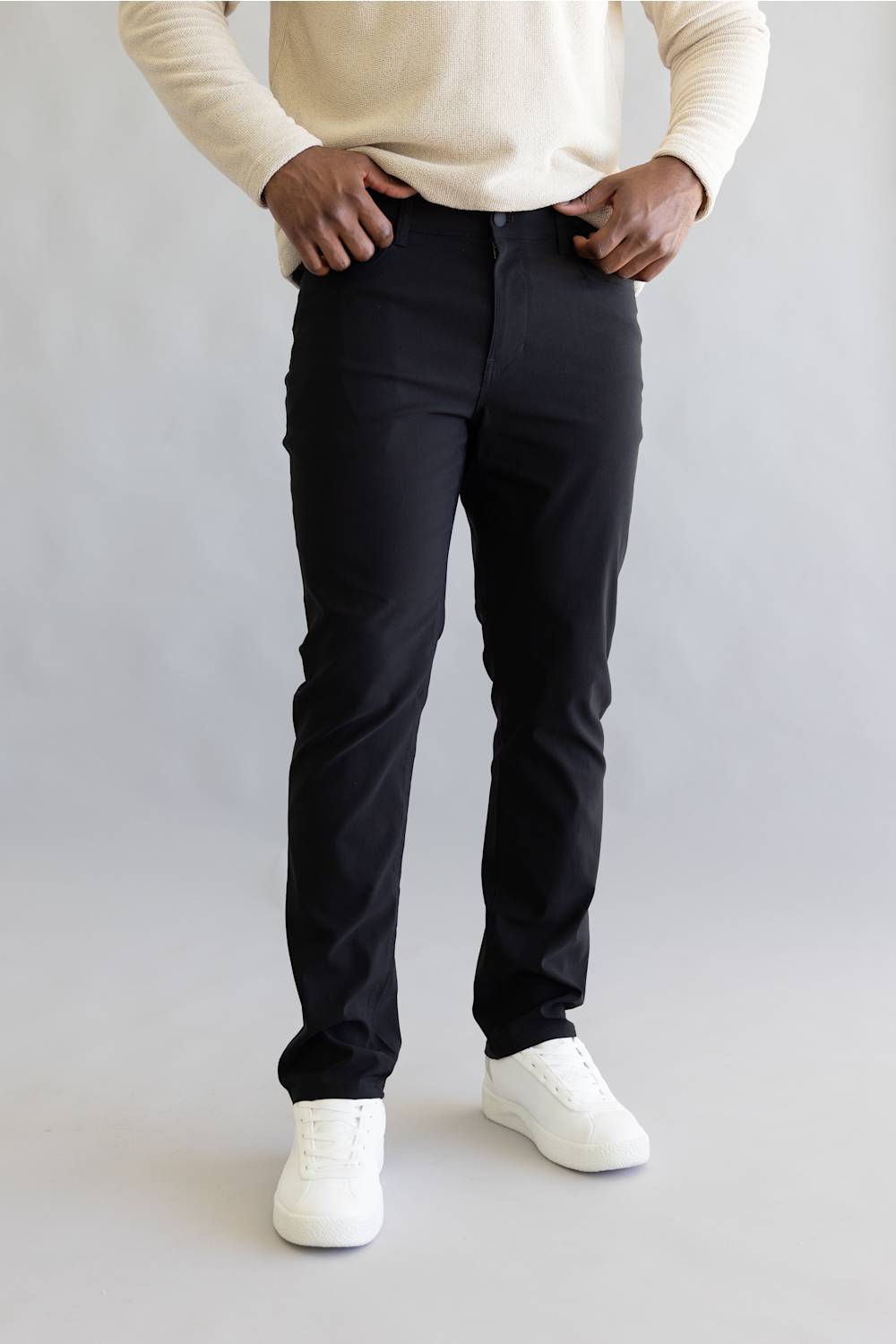 Man wearing black pants and white shoes on a plain background