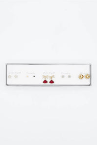 A white rectangular jewelry display tray holding multiple pairs of earrings on a plain white background. The earrings include gold and silver-toned pieces with clear stones and one pair with red stones.
