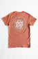A terracotta-colored short-sleeve t-shirt laid flat against a white background, featuring a large circular graphic on the back with the text 'SIMPLY SOUTHERN' and a pink-and-gold monogram logo.