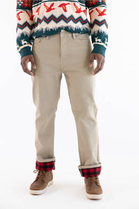 A person wearing beige straight-leg pants with a red and black plaid lining visible at the cuffs, paired with a patterned sweater and brown shoes, against a plain white background.