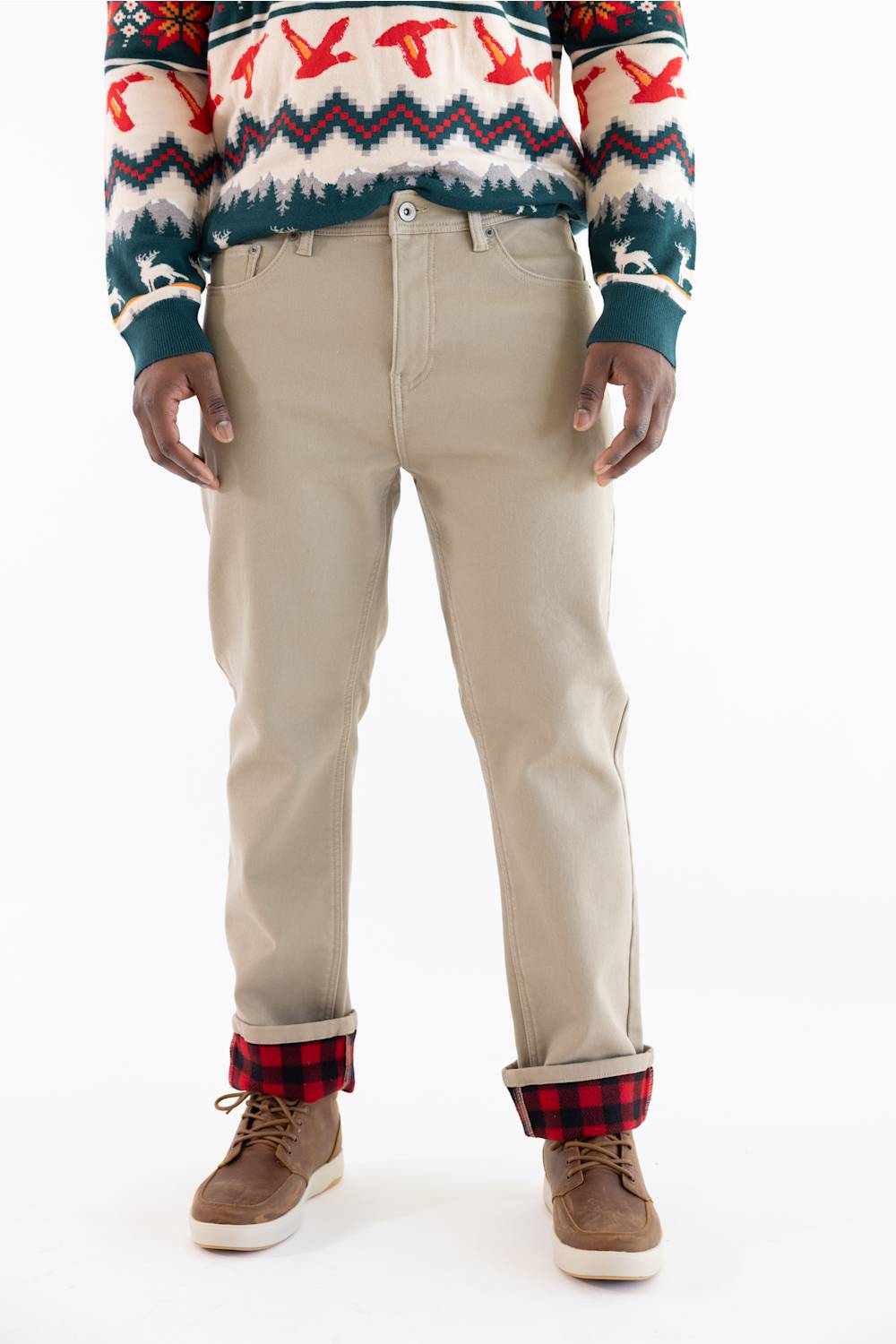 A person wearing beige straight-leg pants with a red and black plaid lining visible at the cuffs, paired with a patterned sweater and brown shoes, against a plain white background.