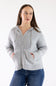 A woman wearing a light gray zip-up hoodie with drawstrings and front pockets, paired with blue jeans, standing against a plain white studio background.