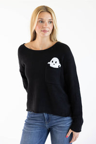 A woman wearing a black knit sweater with a white ghost graphic in a chest pocket, paired with blue jeans, against a plain white background.