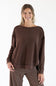 A woman modeling a brown long-sleeve knit top with a wide boat neckline and relaxed fit, paired with brown and white striped pants, against a plain white studio background.