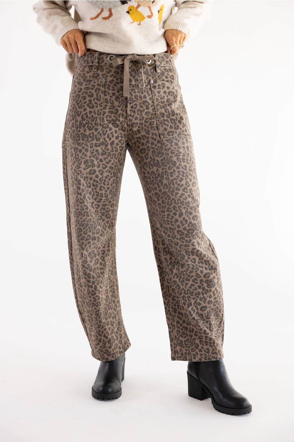  woman modeling cheetah print jeans with black boots and tan sweater 