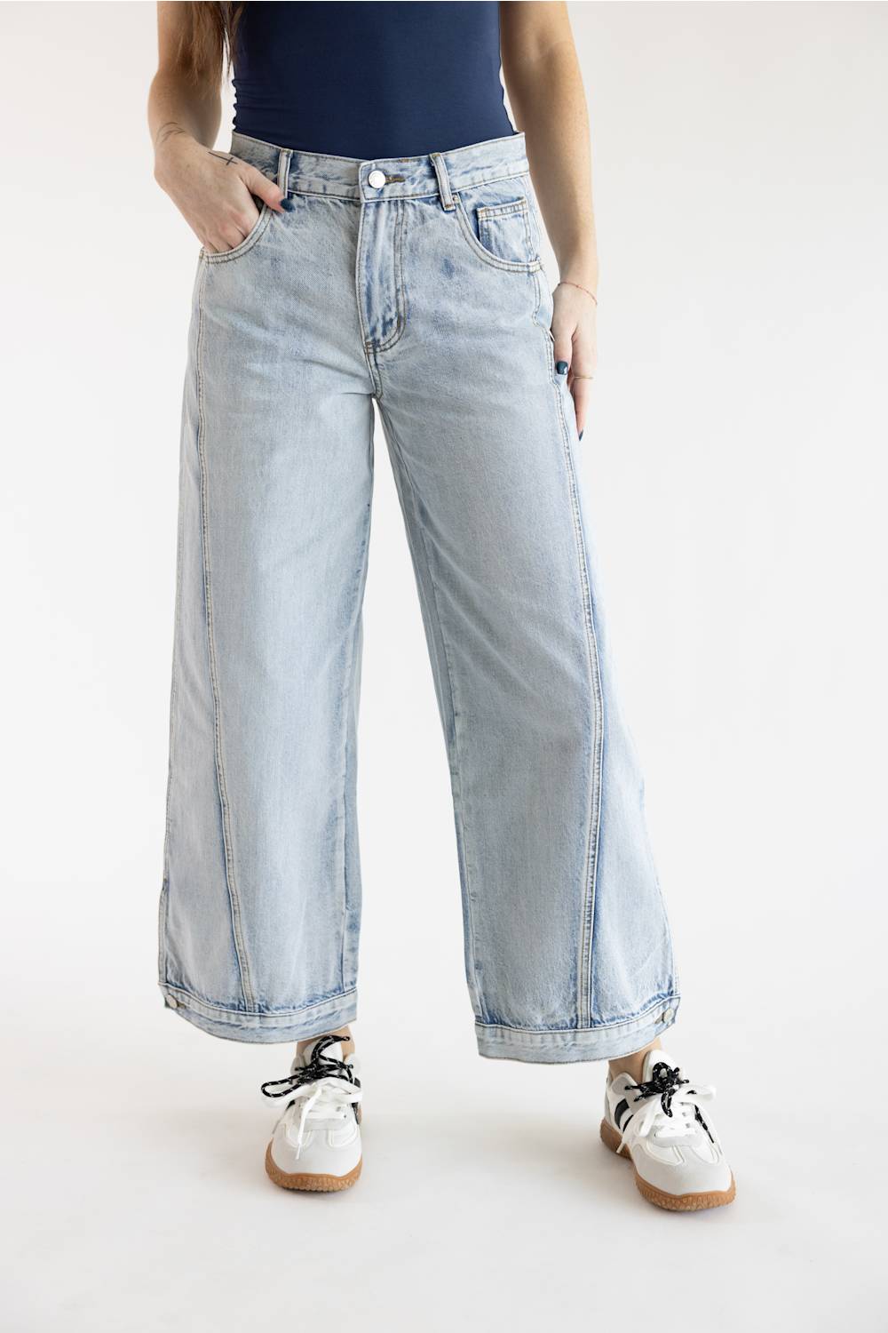 Three-quarter view of Aaron & Amber High Rise Sideseam Detail Wide Leg Jeans in Light Denim, styled with white and brown low-top sneakers against a plain background.