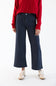 A model wearing dark navy blue pinstriped wide-leg cropped trousers, paired with a red sweater and beige sneakers, shown from the chest down on a white studio background.