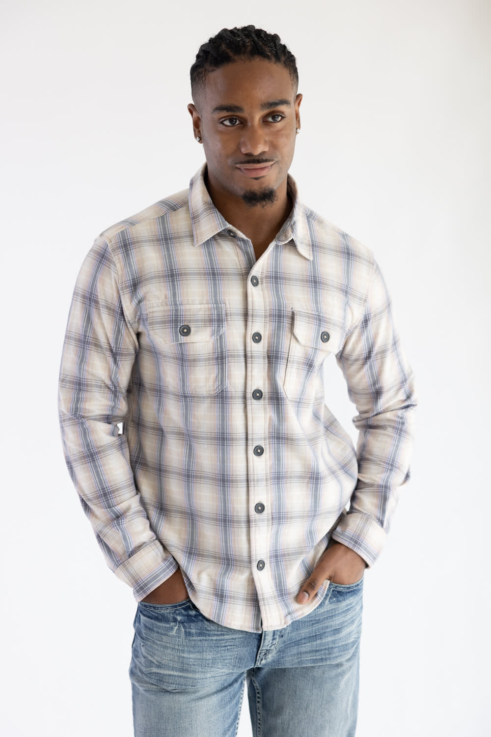 Front view of a man wearing the Hallstatt Knit Button Up Flannel Shirt in Sand with a plaid pattern in blue, beige, and gray, paired with light-wash jeans against a white backdrop.