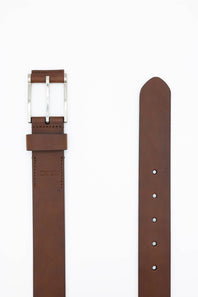 A brown leather belt shown flat on a white background, with the buckle side on the left and the strap end on the right. The buckle is silver-toned metal, and the leather is a medium warm brown.