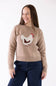 A woman wearing a beige crewneck sweater with a white, brown, and red chicken motif on the front, paired with dark blue jeans, against a plain white background.