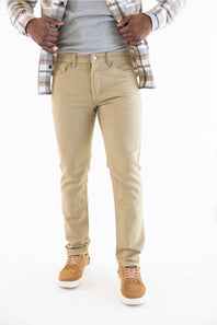 A person wearing slim-fit khaki pants, styled with a gray t-shirt, an open plaid flannel shirt, and tan sneakers, shown from the waist down on a white background.