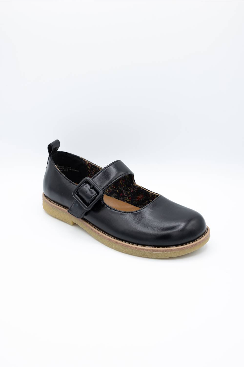 A single black leather Mary Jane shoe with a buckle strap and a tan sole, photographed on a white studio background.